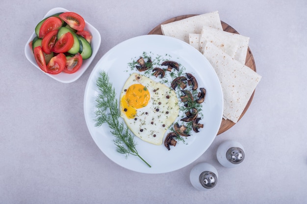 Omelet with pepper and plate of tomato and cucumber.