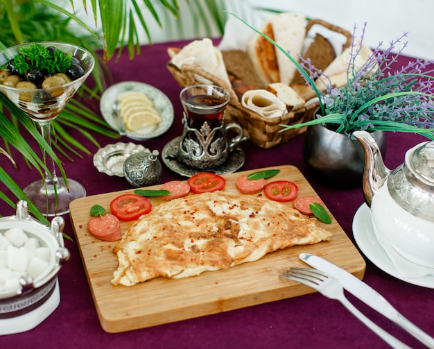 Omelette platter with sausage and tomatoes, served with tea, olive, bread and lemon