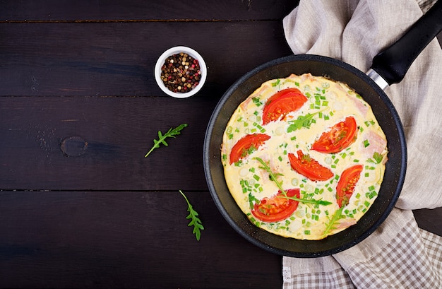 Free photo omelette with tomatoes, ham and green onion on dark table