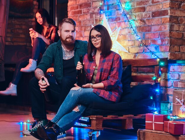 One bearded male and two brunette women Christmas party in a room with loft interior.