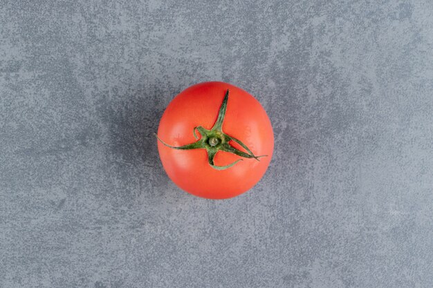 One fresh red tomato on a marble surface