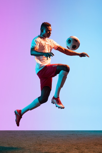 One man professional soccer football player training isolated on gradient wall