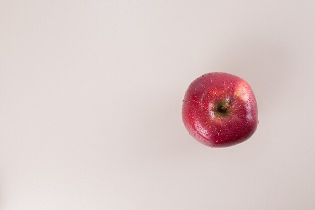 One red apple on white surface .