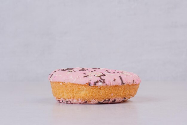 One sweet pink doughnut on white table.