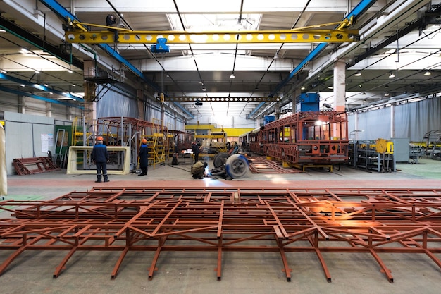 Free photo one working day of modern automatic bus trolleybus car production with unfinished cars workers in protective uniform in factory background automobile assembly line welding arm