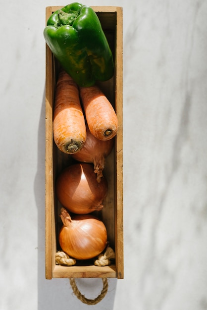 Free photo onion; carrot and green bell pepper in wooden tray