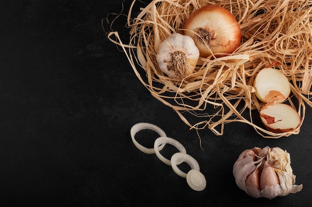 Onion and garlic cloves on black surface.