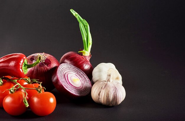 Onion and garlic and hot peppers and tomatoes isolated on a black.