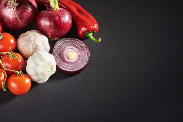 Onion and garlic and hot peppers and tomatoes isolated on a black.