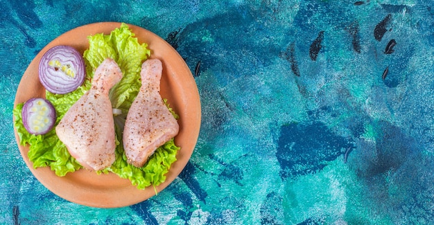 Onion lettuce leaves and chicken drumstick on a clay plate