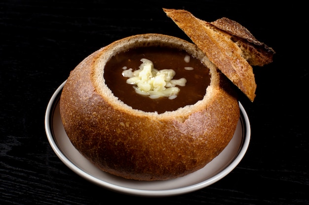 Free photo onion soup in black bread with grated cheese