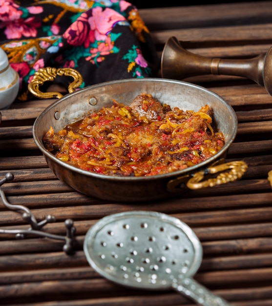 Free photo onion, tomato with beef pieces stew in a copper pan.