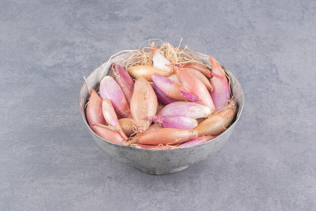 Onions in the iron pot, on the marble surface