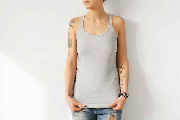 Online shopping. Clothes and apparel. Model posing in blue ripped jeans and stylish grey tank top