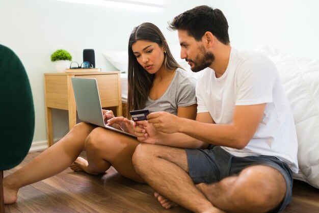 Online shopping concept. Beautiful woman typing the credit card number on her laptop and buying stuff online with her boyfriend