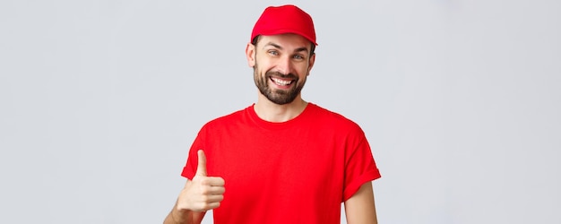 Free photo online shopping delivery during quarantine and takeaway concept friendly cheerful courier in red cap and tshirt uniform encourage make internet orders thumbup in approval or recommendation