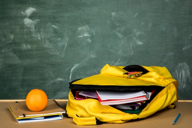 Free photo open backpack and orange on table