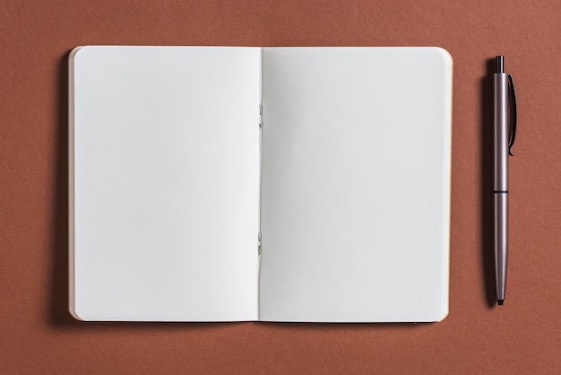 Free photo open blank book with pen on brown background