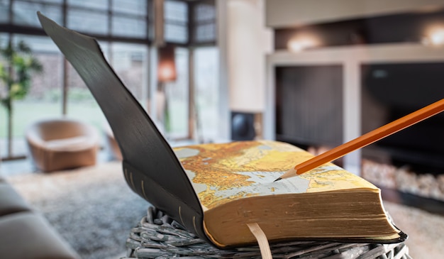 Free photo open book bible with pencil, on the background of the living room. reading a book in a cozy environment.