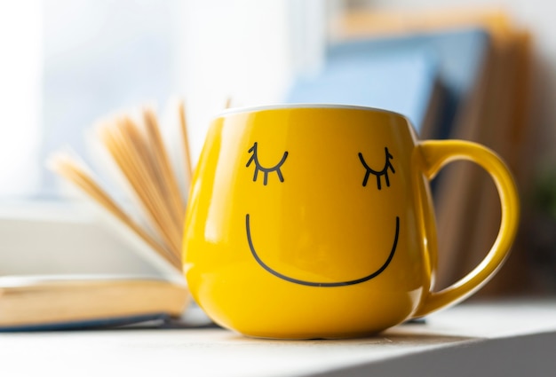 Free photo open book and smiley yellow cup