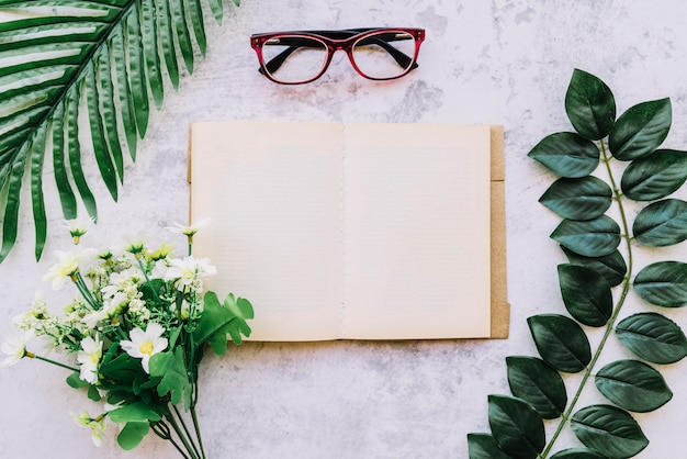 Free photo open book with leaves and flowers