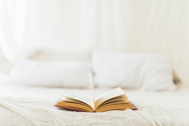 Open hardcover book on bed at home