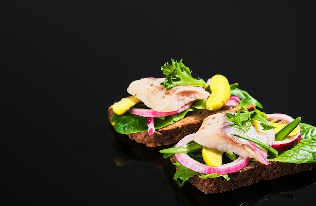 Free Photo open herring sandwich - traditional danish smorrebrod. sandwiches are located on a dark background. close-up, shallow depth of field.