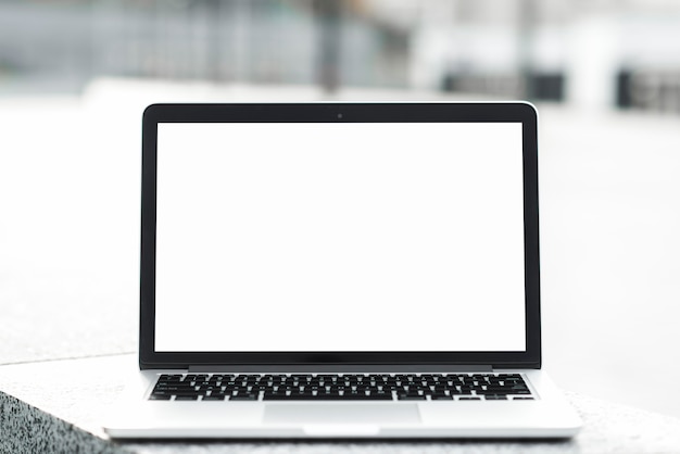 Free photo an open laptop showing blank white screen display on bench against blurred background