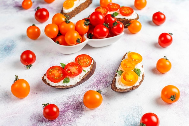 Free photo open sandwiches with cottage cheese,cherry tomatoes and basil.