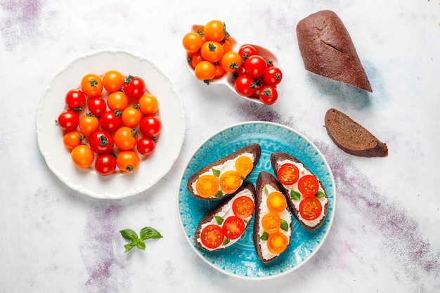 Free photo open sandwiches with cottage cheese,cherry tomatoes and basil.