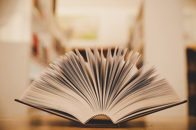 Free photo opened book on the desk and isle of bookshelves in school study class room background