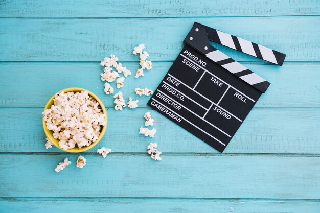 Opened clapperboard near bowl of popcorn