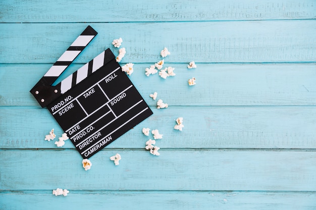 Opened clapperboard near small heap of popcorn