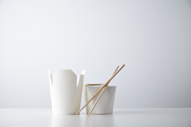 Opened and closed takeaway boxes for chinese noodles presented with chopsticks