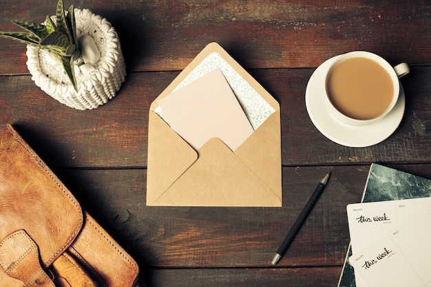 Opened craft paper envelope , autumn leaves and coffee on wooden table