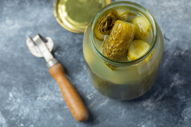 Opened jar full with pickled cucumber on grey background