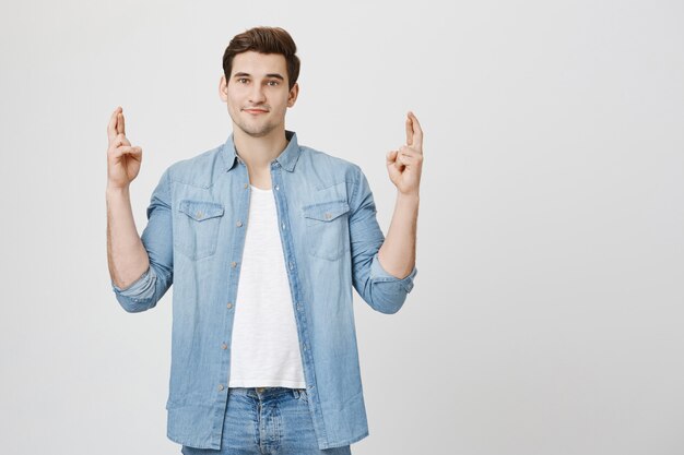 Optimistic hopeful man cross fingers good luck