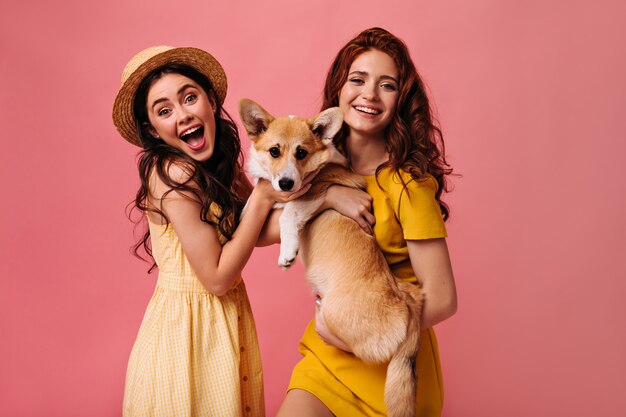 Optimistic ladies in yellow dresses hold dog