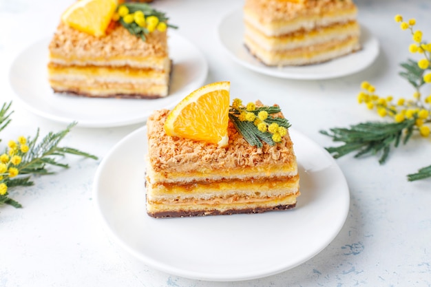 Free photo orange cake decorated with fresh orange slices and mimosa flowers on light