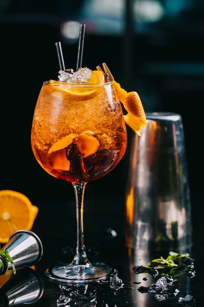 Orange cocktail inside glass with minced ice cubes and pipes.