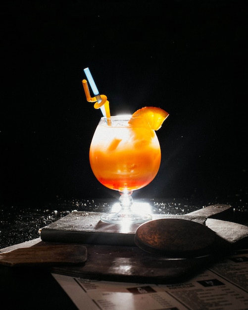 Free photo orange coctail with fresh orange juice ice and straws on book