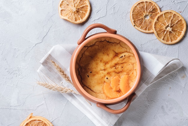 An orange custard pudding with dried fruit slices on white concrete background