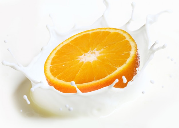 Free photo orange falls into splash of milk