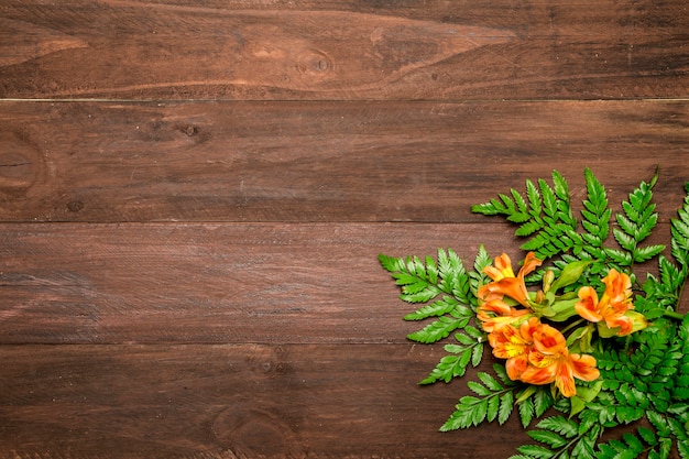 Free photo orange flowers with leaves on wooden background