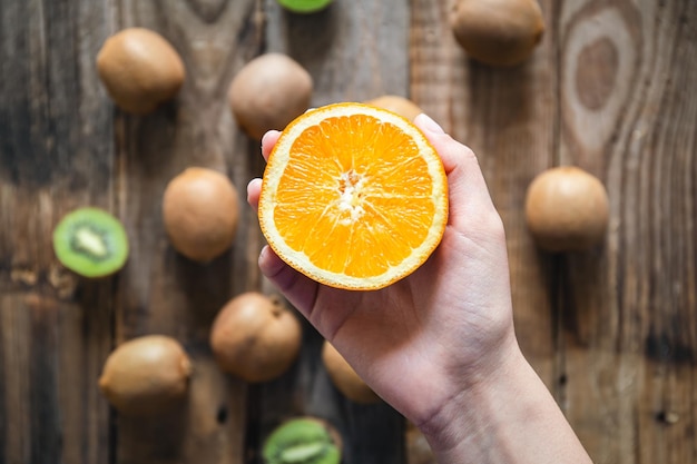 Free photo orange fruit in female hands on a blurred wooden background top view