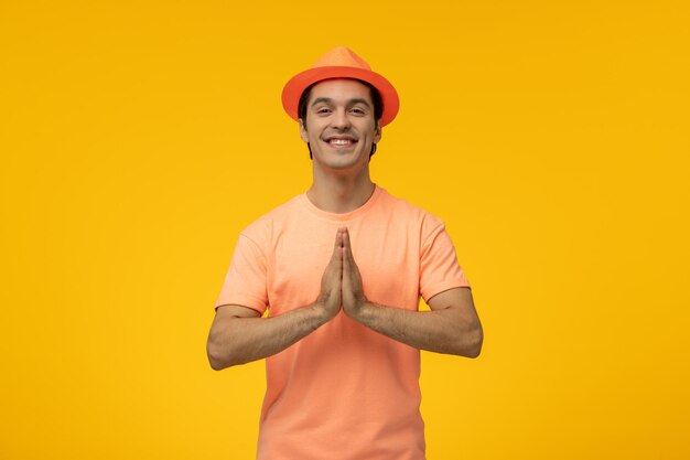 Orange hat cute young guy in orange shirt with the hat praying and smiling