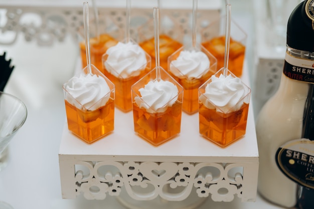 Free Photo orange jelly desserts with whipped cream on a white tray