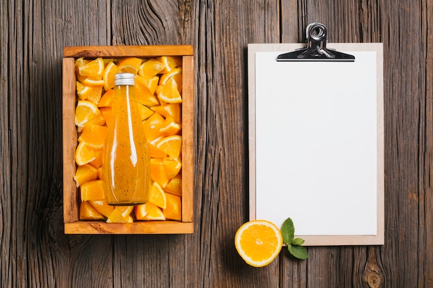 Free Photo orange juice bottle and clipboard on wooden background