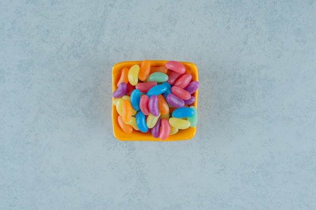 Free photo an orange plate of colorful jelly bean candies on white surface