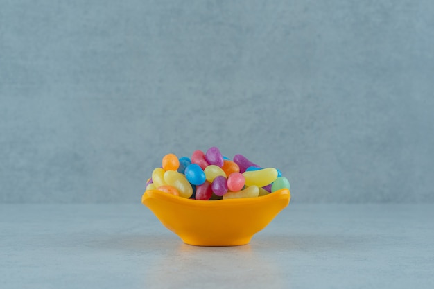 Free photo an orange plate of colorful jelly bean candies on white surface